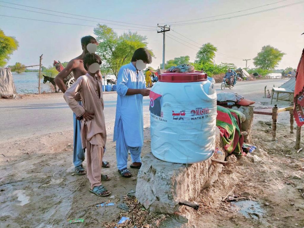 Drei Leute stehen vor einem großen Wasserbehälter