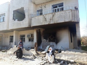 Familie vor zerstörtem Haus in Hezex