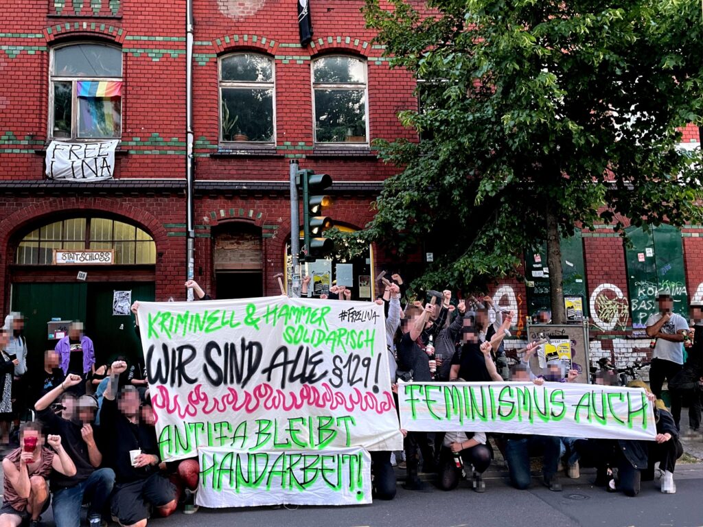 Solifoto mit verpixelten Menschen, die Banner mit der Aufschrift "Kriminell und hammer solidarisch. #FreeLina Wir sind alle §129! Antifa bleibt Handarbeit!" und "Feminismus auch" halten