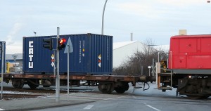 Foto zeigt den ersten Uranerzkonzentrat beladenen Container auf dem zweiachsigen Containertragwagen direkt hinter der Rangierlok bei der Ausfahrt vom Süd-West Terminal im Hamburger Hafen
