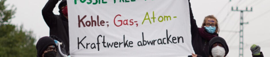 4 Leute mit Bannern sitzen auf Schienen. Der Infotext sagt "Unterstützt Ava und Ralph" und lädt zu zwei Gerichtsverhandlungen am 23.6.2023 und am 14.7.2023 ein.