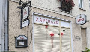 Front des Zapfhahn. Die 88 fehlt mittlerweile im Namen, das Namensschild ist löchrig. Farbflecken und Graffiti sind ebenfalls noch vorhanden